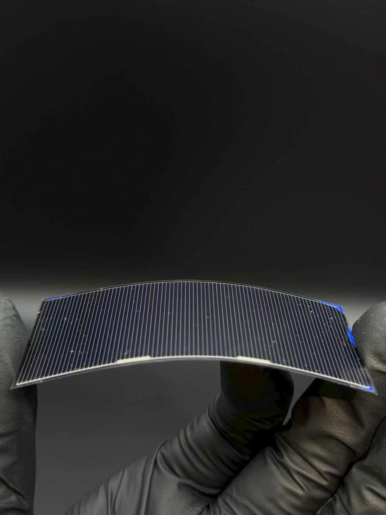 Flexible HJT solar cell sample bent between gloved fingers